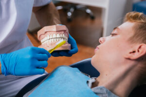 dentista enseñando a cepillar los dientes a niño que mira y aprende